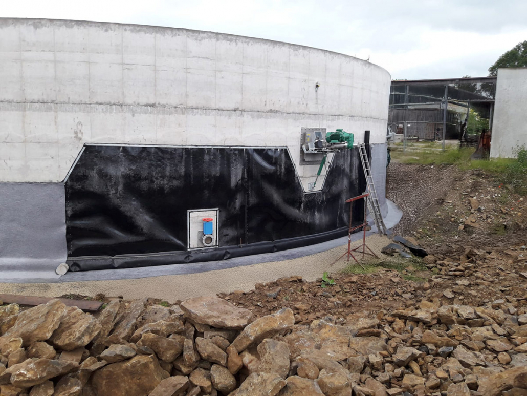 Rundbehaelter-siwoplan-005 Runder Behälter mit Betonwänden und schwarzer Außenabdichtung auf Baustelle.